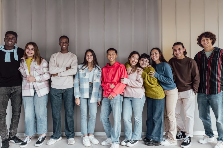 Happy multiracial group of teenagers having fun inside universit